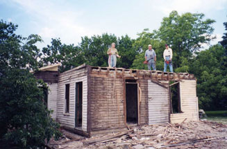 Three People Standing on a Disintegrated House